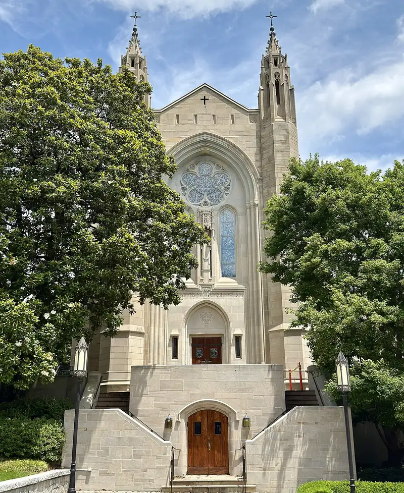 Catedral de Cristo Rey de Atlanta, fachada neogótica de piedra clara con rosetón y dos torres, entre árboles