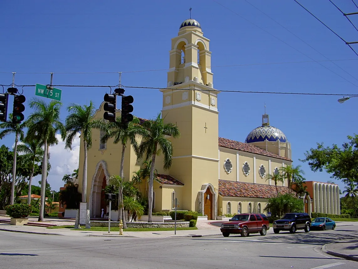 Catedral de Santa María de Miami, de color amarillo, con su campanario y una cúpula de azulejos azules, en la esquina de la calle 75